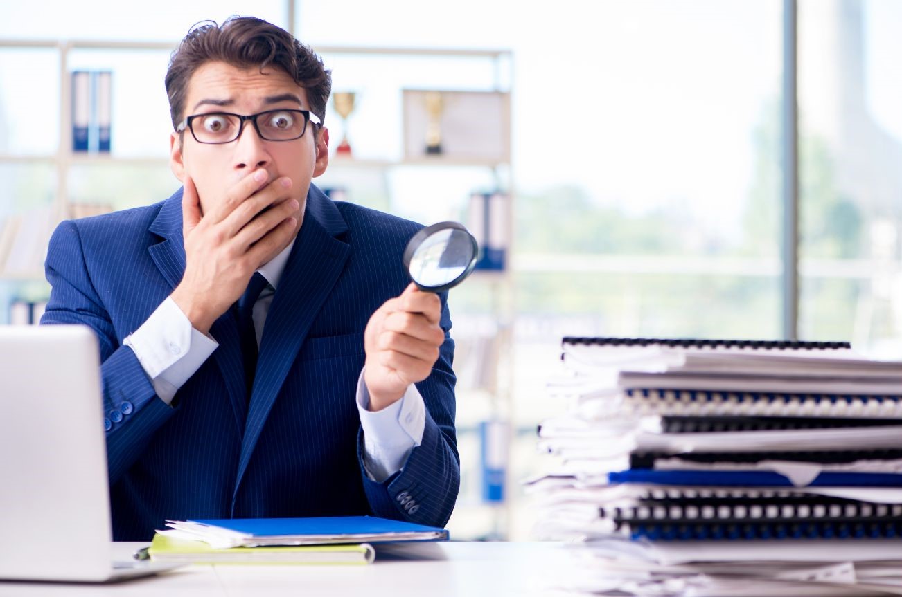 Business man with magnifying glass finding an error