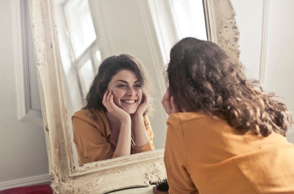 Smiling woman looking at herself in mirror